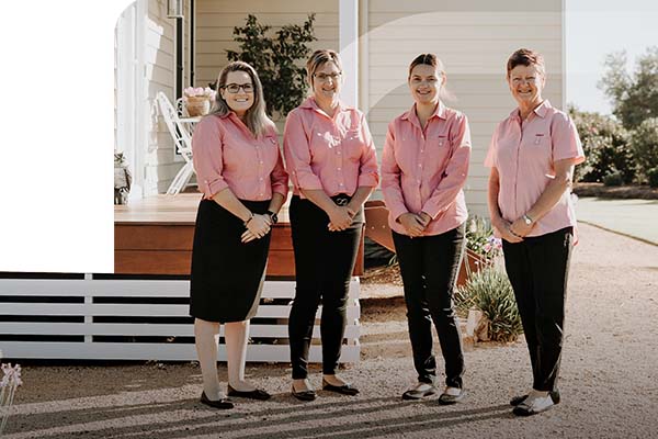 Four female staff members outside a house